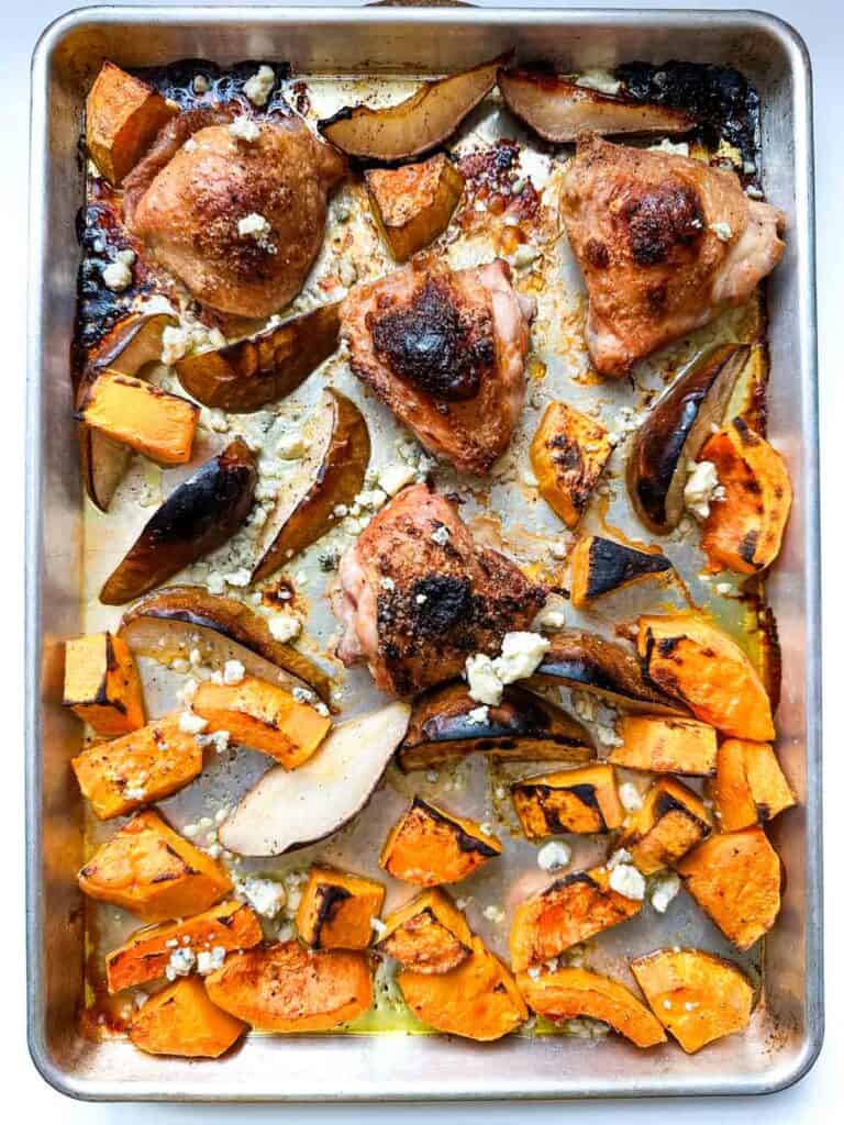 A sheet pan with roasted chicken, squash and pears topped with crumbled blue cheese.