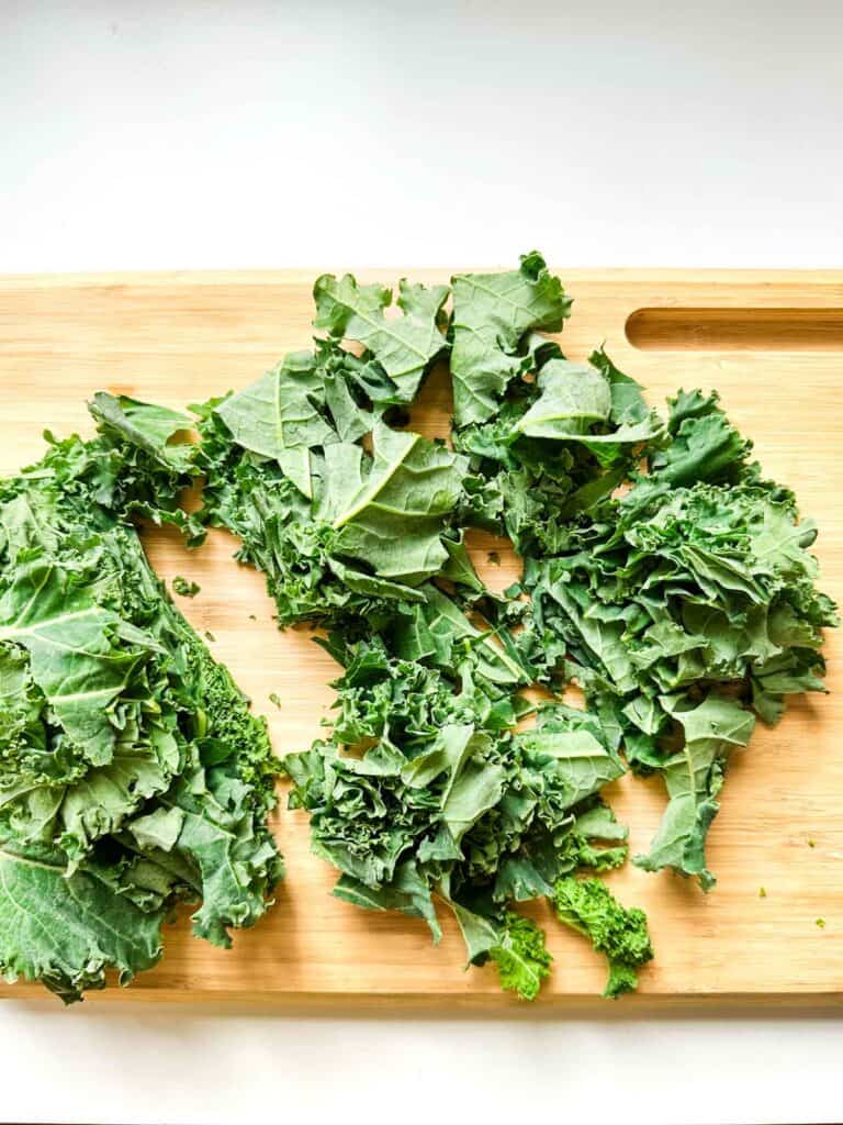 A cutting board with cut up kale.