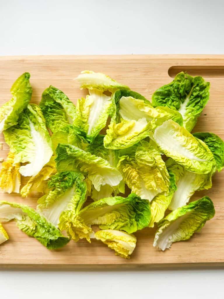 A cutting board with little gem lettuces separated into whole leaves.