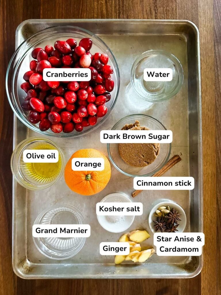 An overhead view of a sheet pan filled with all of the ingredients required to make spiced cranberry sauce.