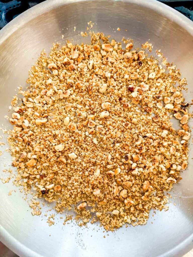 Toasted hazelnuts and breadcrumbs in a saute pan.