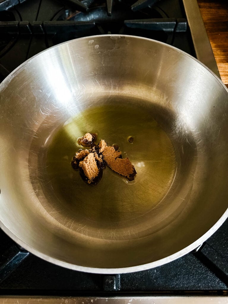 Sugar and olive oil in a saucepan on the stove ready to bloom spices.