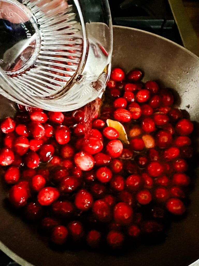 Grand Marnier, an orange liqueur, being added to cooking cranberry sauce.