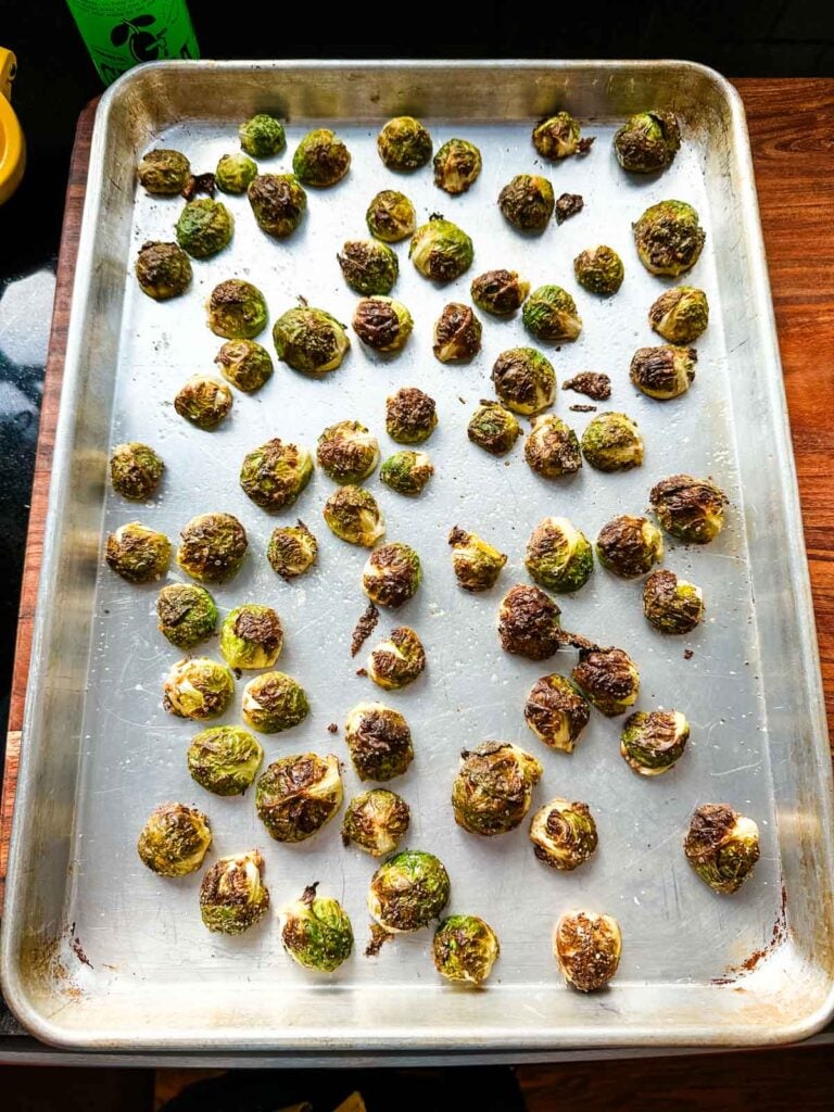 Sheet pan of partially roasted brussels sprouts removed from the oven and ready to have miso glaze added to them.