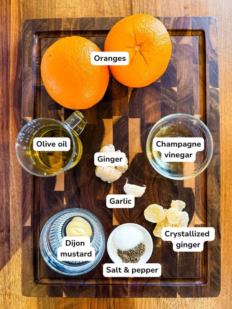An overhead view of the ingredients required to make ginger vinaigrette on a dark cutting board.