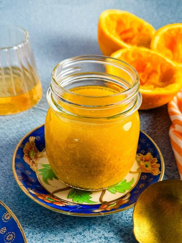 A closeup view of a jar of vinaigrette on a blue and orange saucer.